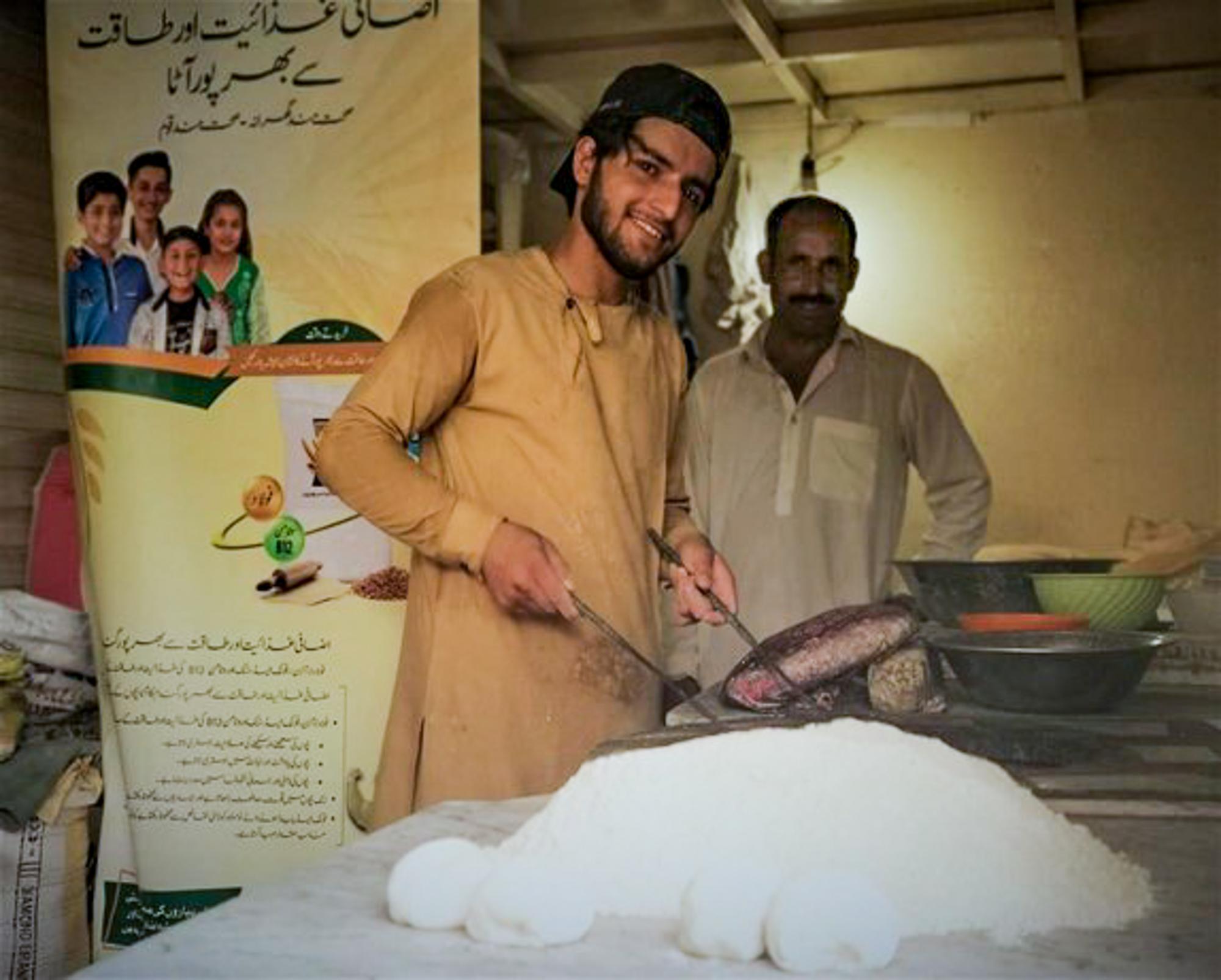 Two men gathered around fortified wheat flour.