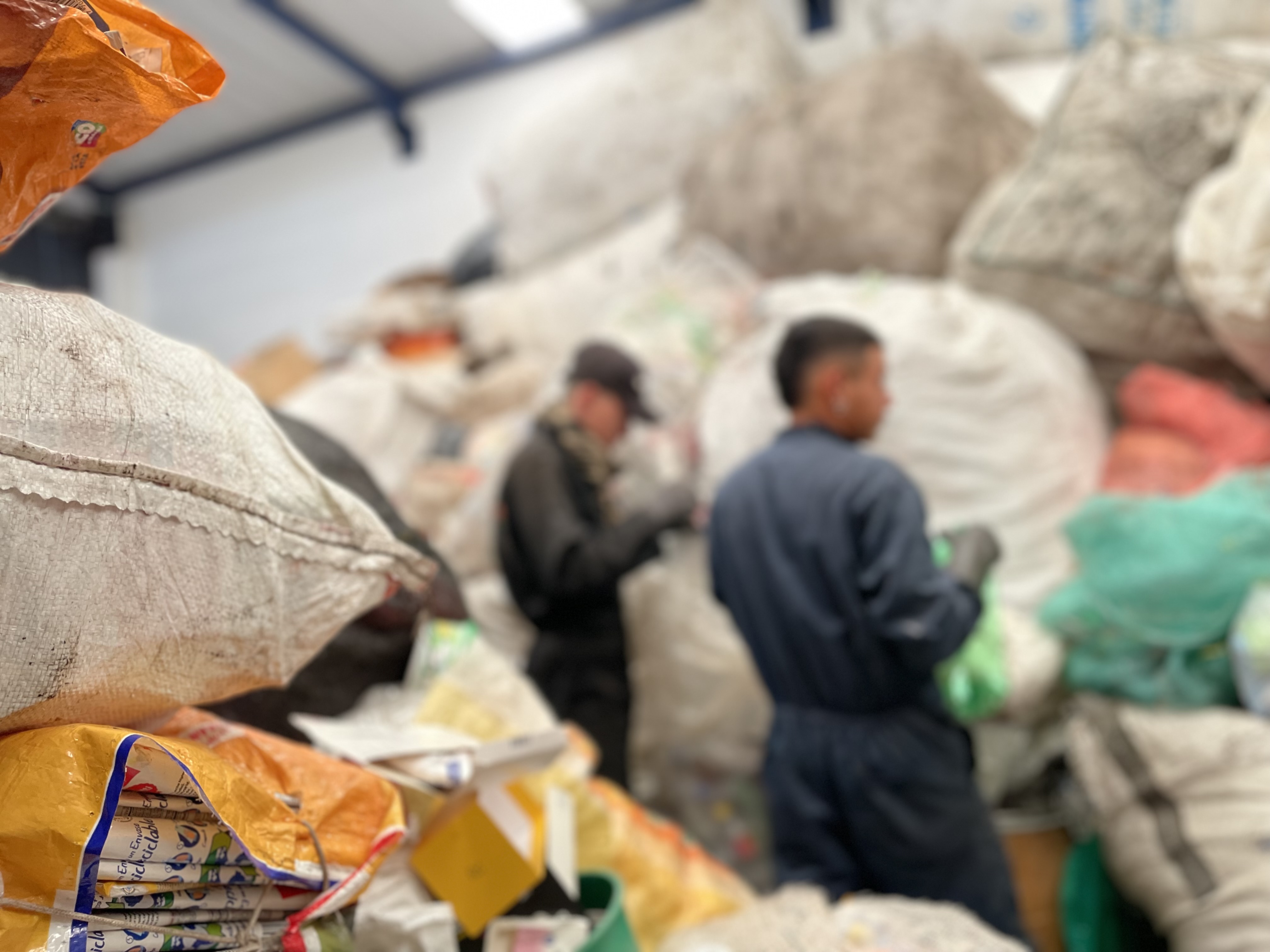 People standing in front of bags of recyclable waste; Photo: WFP/Jessika Camargo