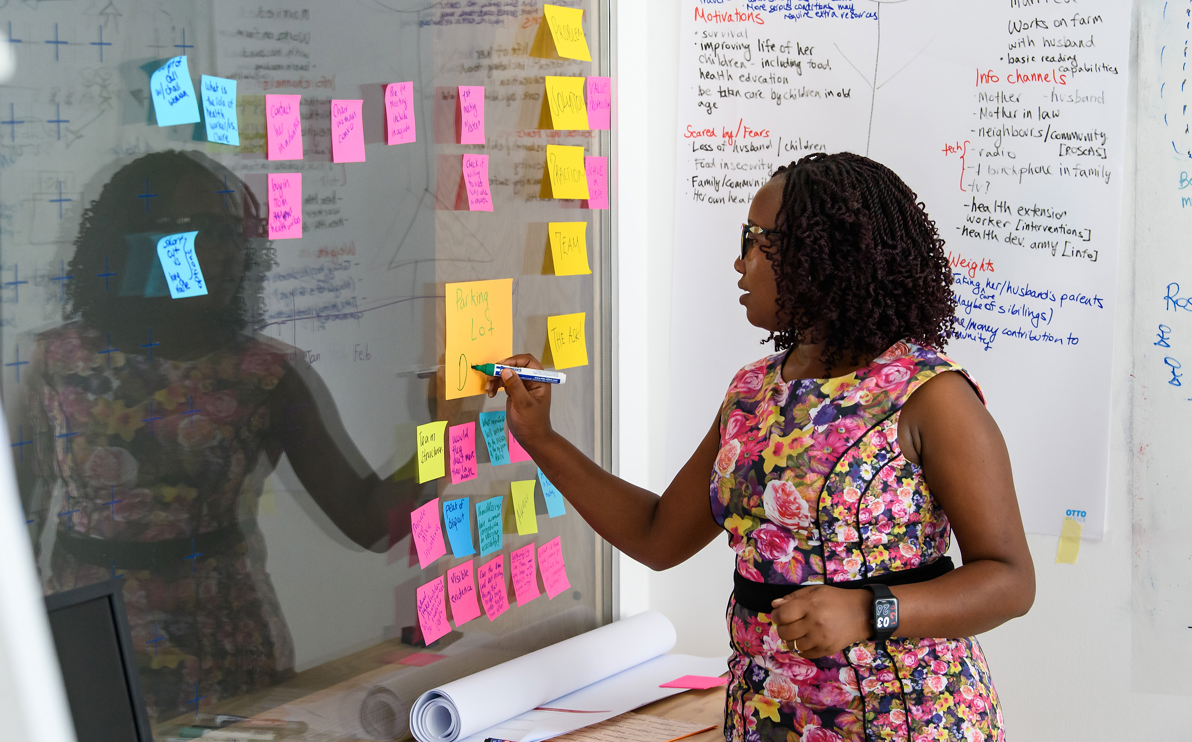 A women writing on a sticky note stuck to a wall