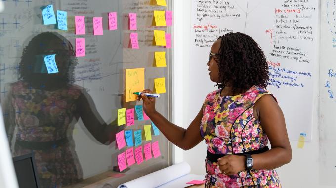 A women writing on a sticky note stuck to a wall