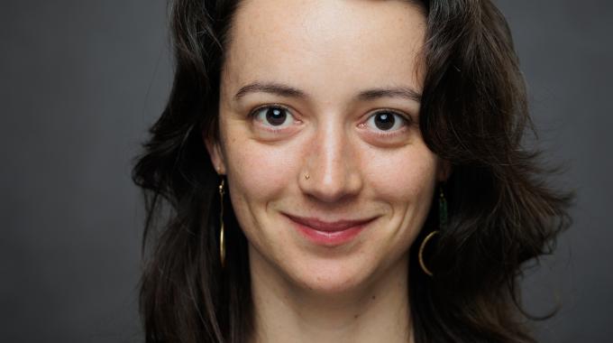 Photo of Margherita Philipp smiling to camera on a dark grey background.