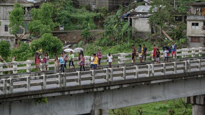 A group ofpeople walking across a bridge in the rain.