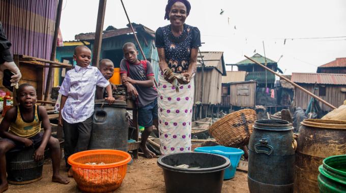 A woman holding her home-grown fish in her home in Nigeria