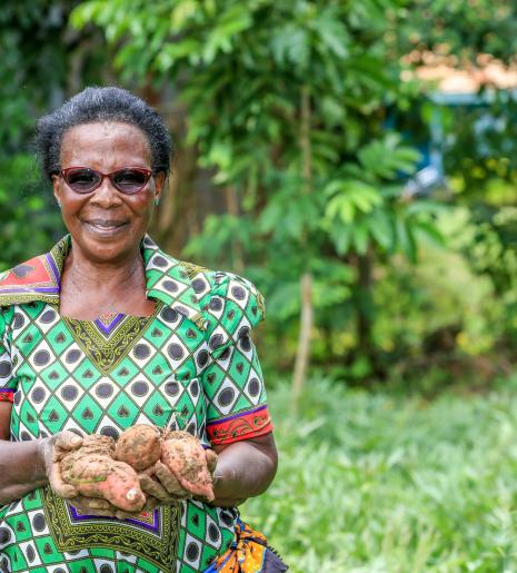 Hannah Karanja, a farmer in Busia County, Kenya, holds sweet potatoes she grew on her farm.