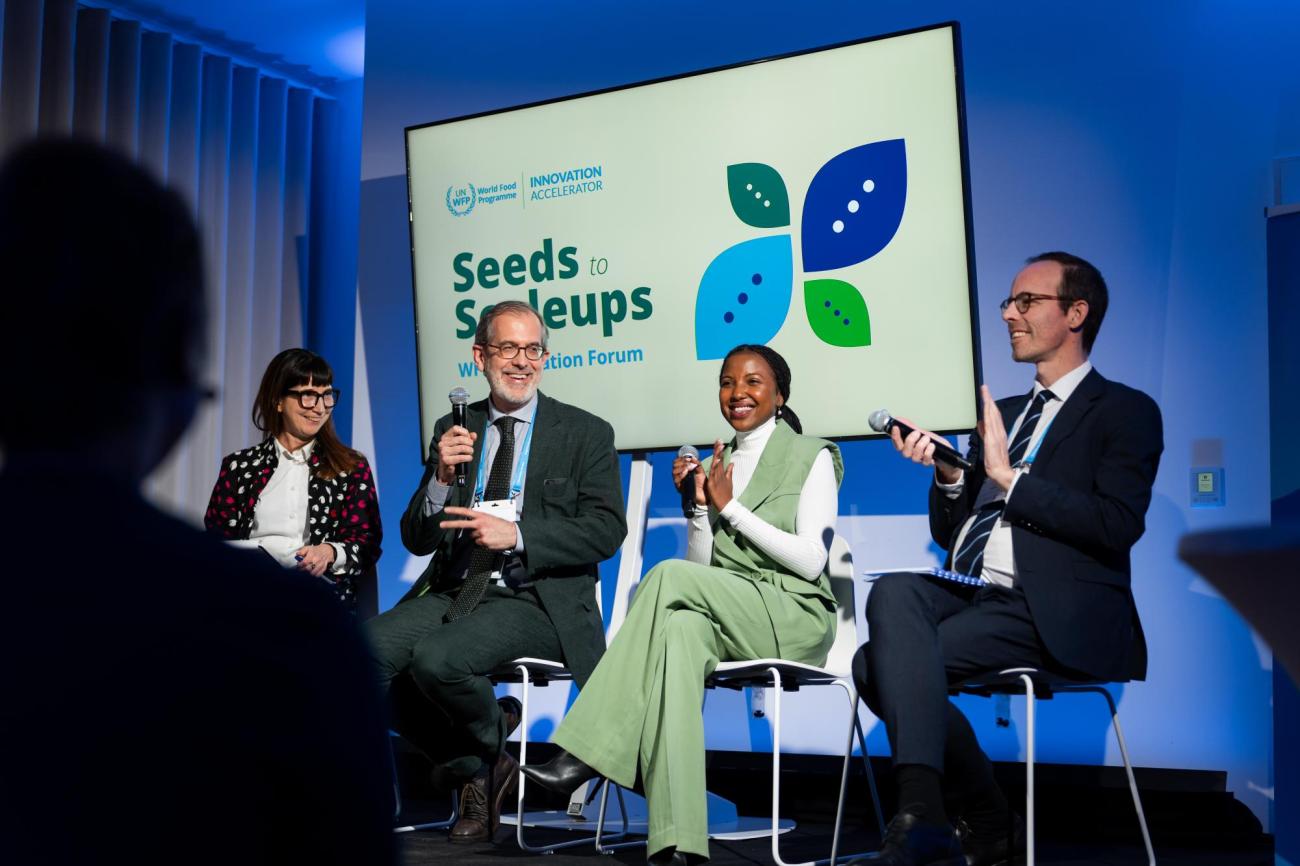 Group smiling while sitting on a stage talking.