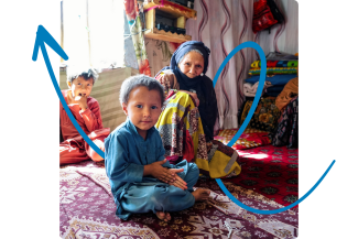 A woman and a child sit on the floor, positioned in front of a striking blue arrow on the wall.