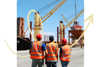 Three men in bright orange WFP vests stand before a ship, likely coordinating food distribution logistics.