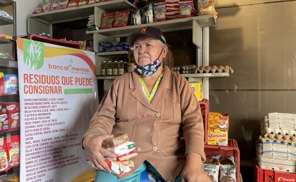 Woman in a storefront holding up food products. Photo: WFP/Jessika Camargo