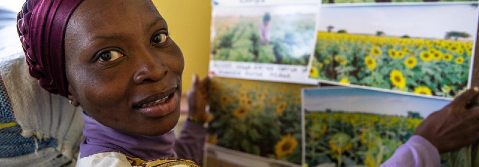 Coletha Raphael proudly shows a photograph capturing the flourishing sunflower field from the previous season. © WFP/Gabriela Vivacqua