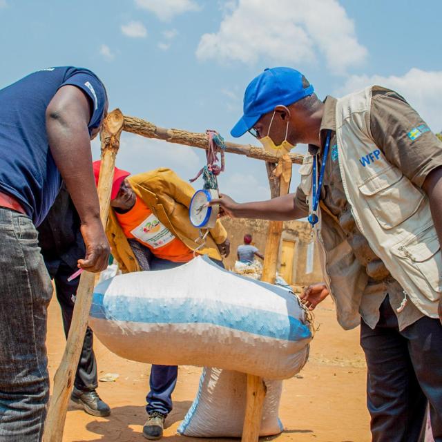 WFP staff Pennias Mulauzi helping farmers weigh crops for the market WFP_Paul MboshyaJR