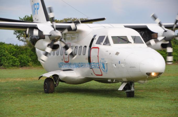 UNHAS plane taxis on grass airstrip with palm trees in the background. I © WFP/Sean Rajman