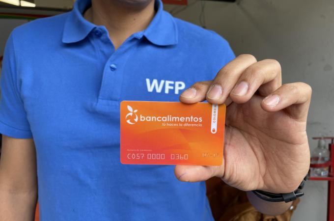 Man holding up a Bancalimentos card; Photo: WFP/Jessika Camargo